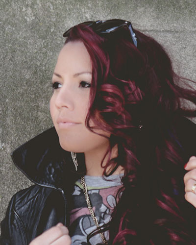 Woman with curly hair and leather jacket looking away.
