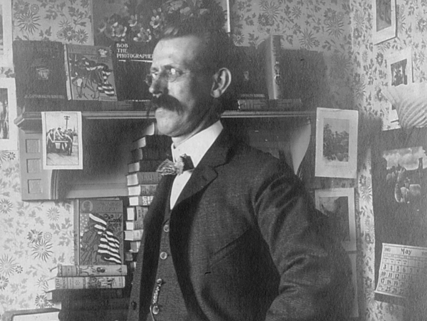 Man with mustache standing in decorated room.